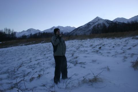 2003 Jeep TJ - A person stands in a snow-covered field, looking out at a mountain range under a twilight sky.