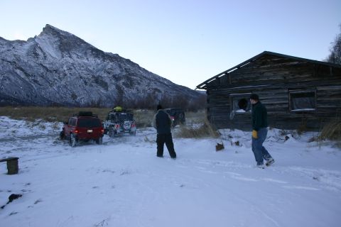2003 Jeep TJ - Two 2003 Jeep TJs are parked in the snow near an old cabin with a mountain in the background.