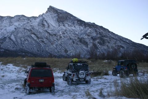 2003 Jeep TJ - Three Jeep Wranglers are parked in a snowy area with a large, snow-covered mountain dominating the background.