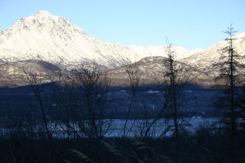 2003 Jeep TJ - A winter landscape features snow-capped mountains overlooking a frozen body of water, with silhouetted trees in the foreground.