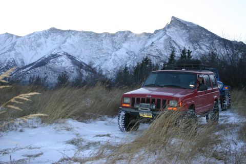 2003 Jeep TJ - Two Jeeps navigate a snowy mountain landscape, one red Cherokee XJ and one blue Jeep.