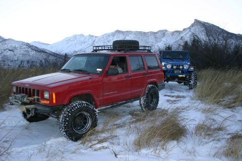 2003 Jeep TJ - Two Jeeps, a red Cherokee XJ and a blue Wrangler, navigate a snowy mountain path.