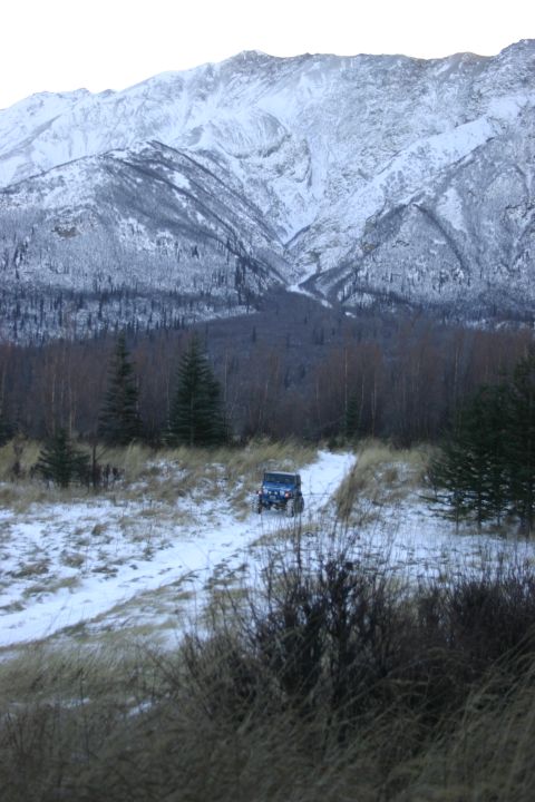 2003 Jeep TJ - A blue 2003 Jeep TJ navigates a snowy trail with a , snow-capped mountain range looming behind it.