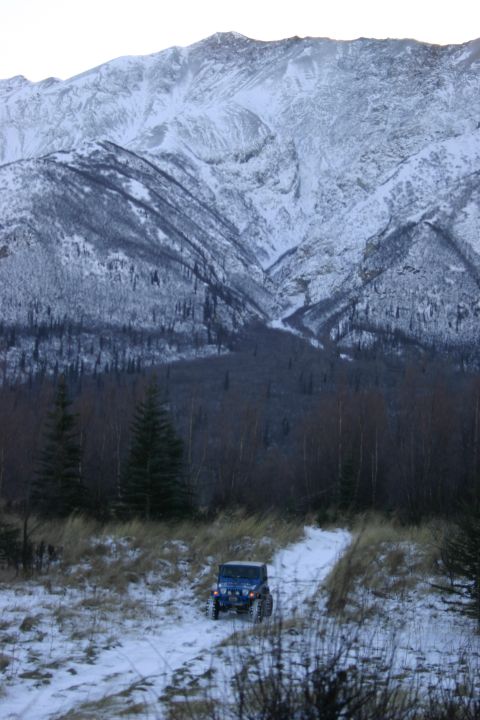 2003 Jeep TJ - Jeep TJ navigating a snowy path with a large, snow-covered mountain range in the distance.
