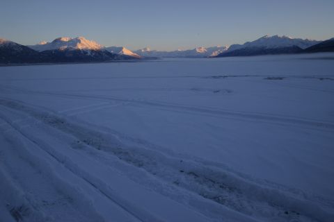 2003 Jeep TJ - A vast, snow-covered plain stretches towards distant, sunlit mountains under a pale blue sky.