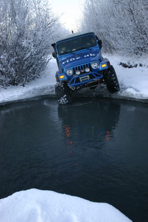 2003 Jeep TJ - Blue 2003 Jeep TJ navigates icy water in a snowy winter landscape.