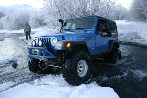 2003 Jeep TJ - Blue 2003 Jeep TJ Rubicon navigates icy water in a snowy landscape.
