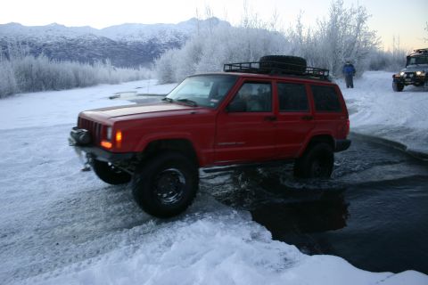 2003 Jeep TJ - Two Jeeps navigate a snowy, icy terrain with mountains in the distance.