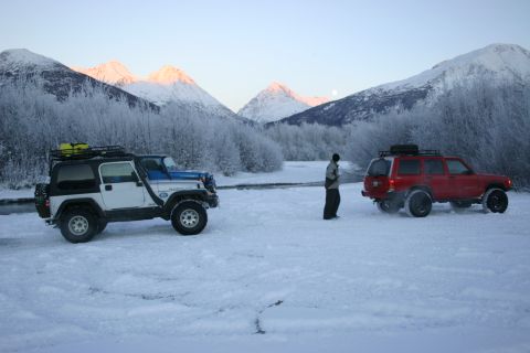 2003 Jeep TJ - Two Jeep SUVs and a red SUV parked in a snowy landscape with mountains under a clear sky.