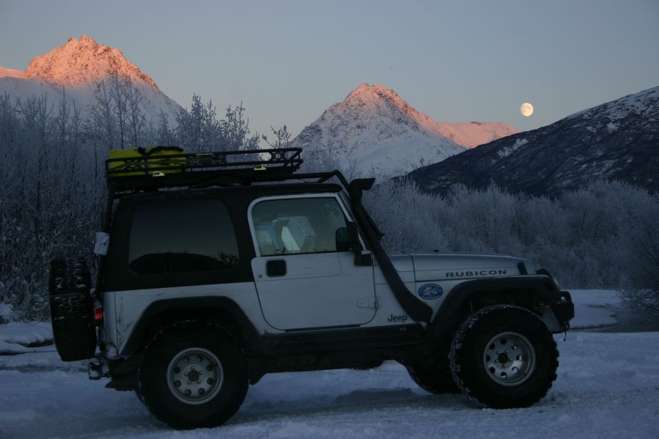 Silver 2003 Jeep Wrangler Rubicon side view in snow with mountains and moon