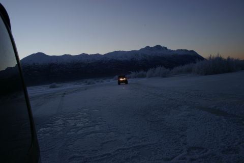 2003 Jeep TJ - A Jeep navigates a snow-covered road as twilight settles over the mountains.