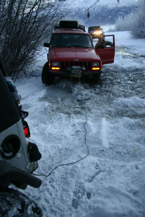 2003 Jeep TJ - Two Jeeps in a snowy landscape, one is stuck and being pulled by a winch cable.
