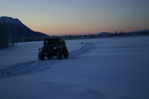 2003 Jeep TJ - A Jeep Wrangler navigates a snow-covered landscape under a twilight sky.