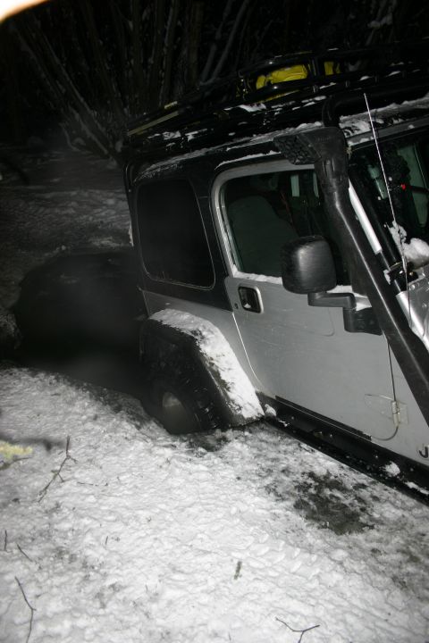 2003 Jeep TJ - Silver Jeep TJ with snorkel and roof rack stuck in snow during winter conditions.