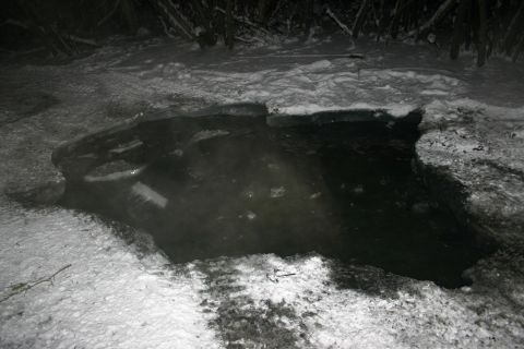 2003 Jeep TJ - A dark hole in the ice, filled with water and surrounded by snow, shows signs of tire tracks.