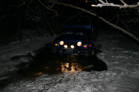 2003 Jeep TJ - Jeep TJ navigates a snowy trail with a muddy puddle at night.