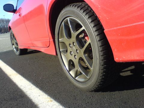 2005 Dodge SRT-4 - Close-up of the side of a red 2005 Dodge SRT-4, focusing on the wheel and fender.