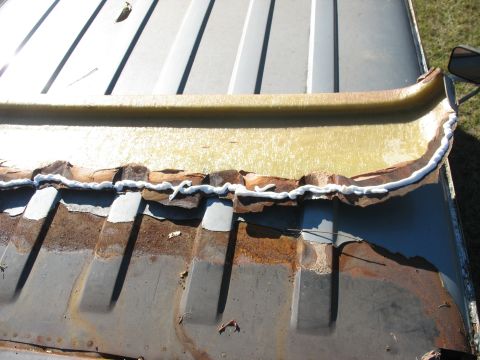 1986 Ford C-350 (Centurion Conversions) - Close-up of a damaged and rusted vehicle roof edge, showing repair work with sealant.