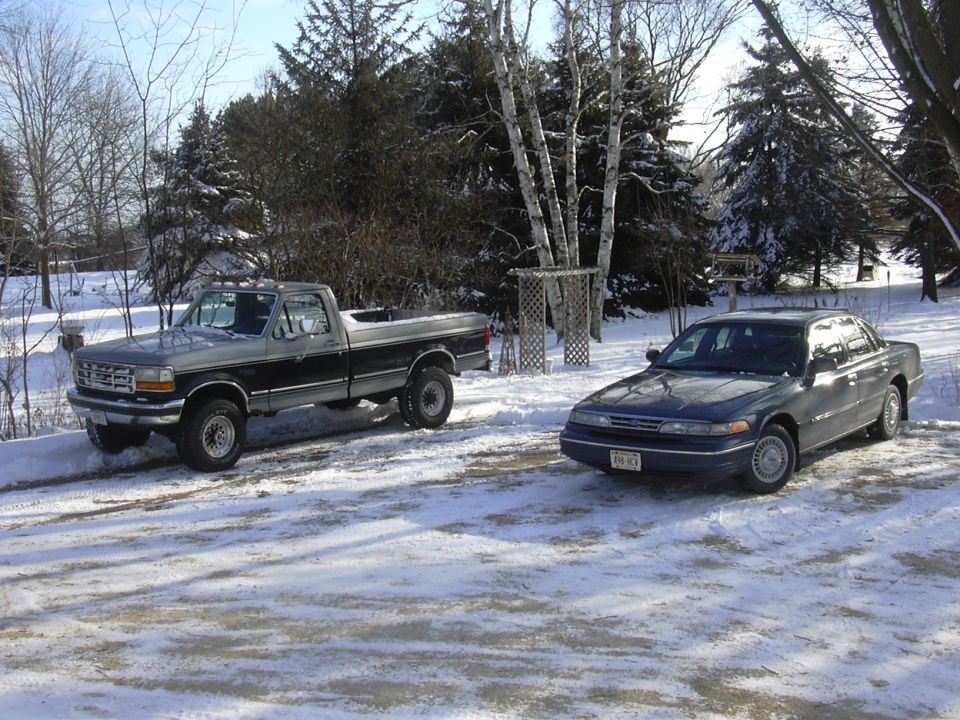1995 Ford F-Series truck and a dark blue Ford Crown Victoria parked in snow