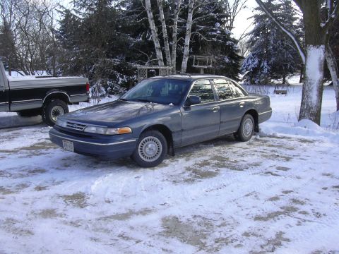 1996 Ford Crown Victoria - A 1995 Ford Crown Victoria is parked in a snowy lot next to a pickup truck.