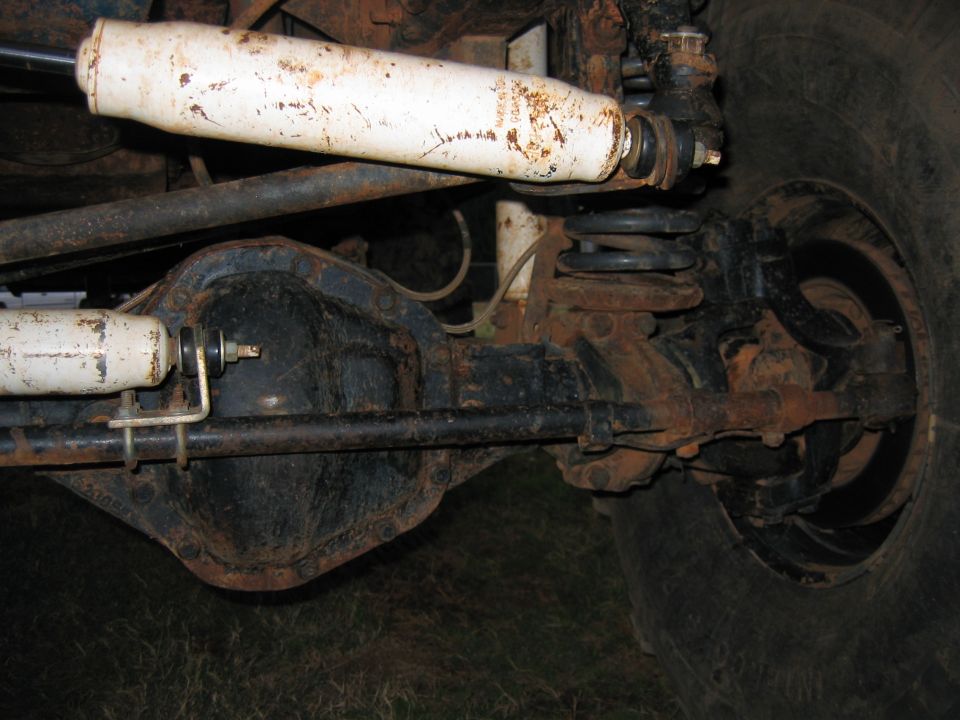 close-up of rusty rear axle, shock absorber, and coil spring on a vehicle