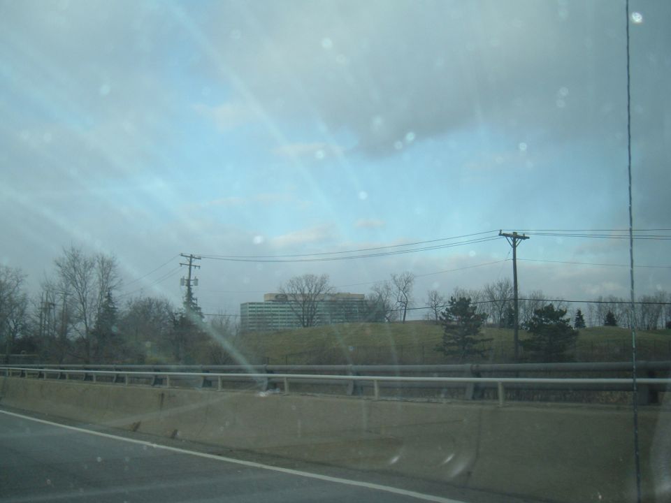 Highway roadside view with guardrail and distant buildings