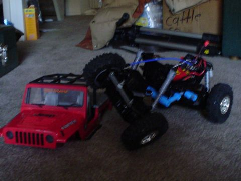 2006 Jeep TJ - A red RC Jeep body is positioned next to its chassis on a carpeted floor.