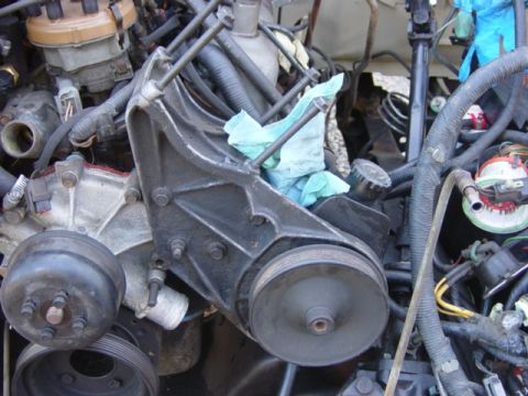 1991 Ford Bronco - Close-up view of engine components, including a bracket and pulleys, with blue shop towels visible.