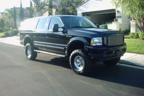 2001 Ford Excursion - This lifted Ford Excursion SUV is parked on a residential street, showing its front and side profile.