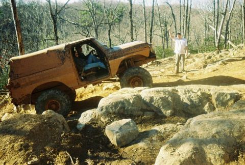 1993 Ford Bronco - An off-road vehicle navigates a challenging rocky terrain with a person observing.