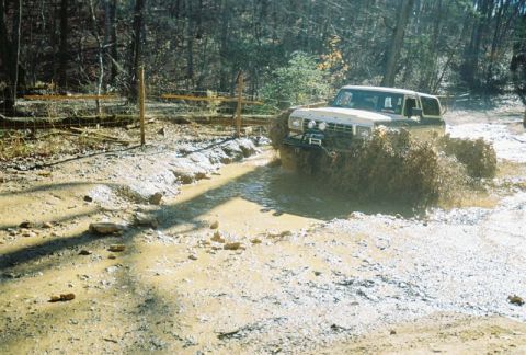 1993 Ford Bronco - This 1993 Ford Bronco navigates a muddy trail, kicking up a significant amount of dirt and water.