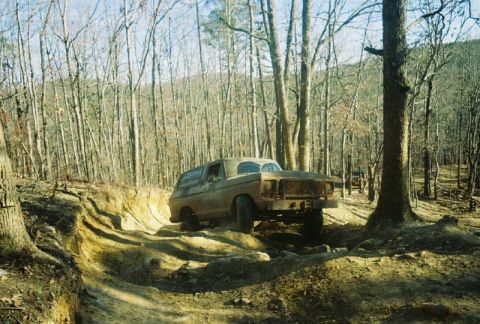1993 Ford Bronco - A 1978 Ford Bronco navigates a challenging off-road trail through a dense forest.