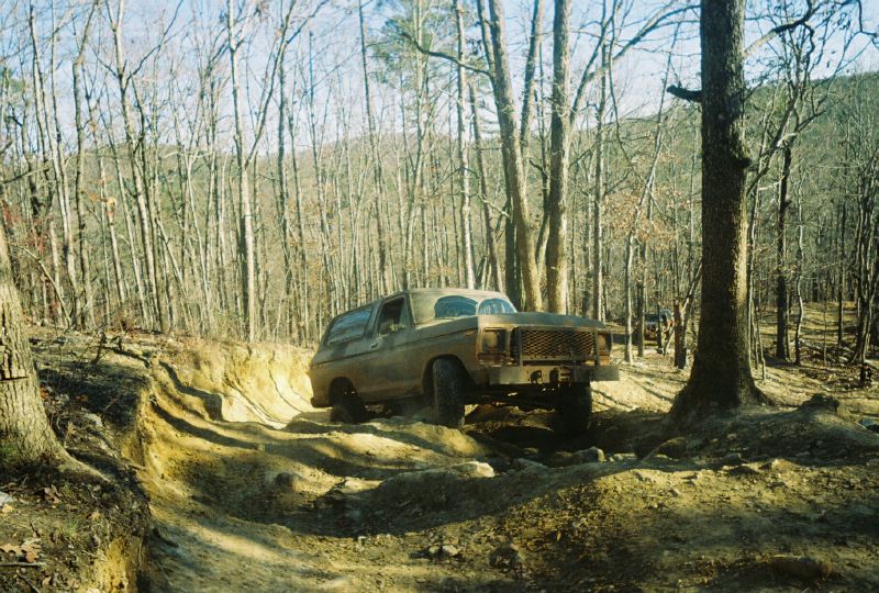 Brown 1978 Ford Bronco off-roading in a wooded area