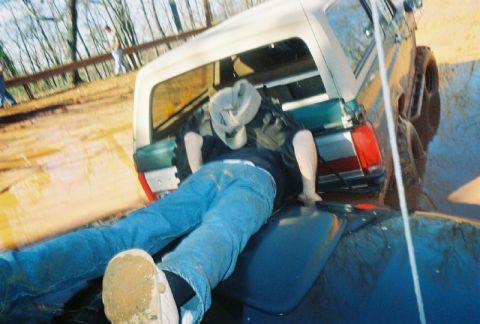 1993 Ford Bronco - A person is stuck in the mud with a white Ford Bronco.