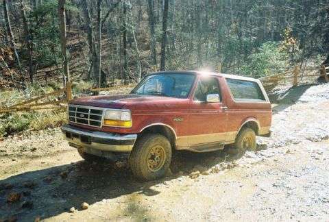 1993 Ford Bronco - Red 1993 Ford Bronco navigates a challenging dirt path.