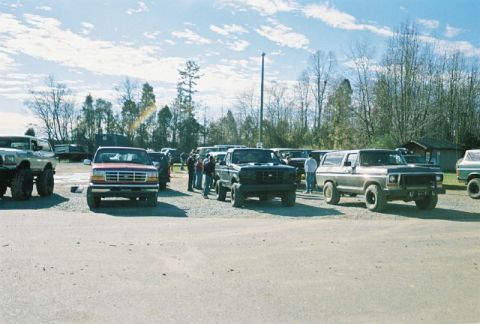 1993 Ford Bronco - A group of Ford Bronco and F-Series trucks are parked outdoors on a sunny day.