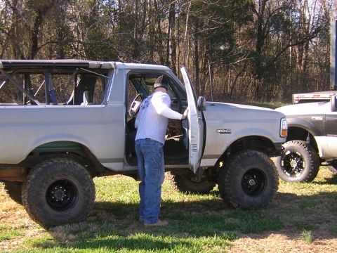 1979 Ford Bronco - Modified Ford Bronco with roll cage and large tires, parked next to another truck.
