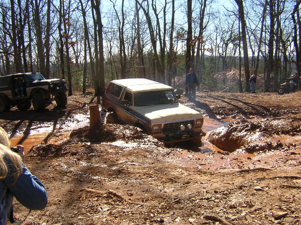 Ford Bronco stuck in mud pit, another SUV nearby in woods