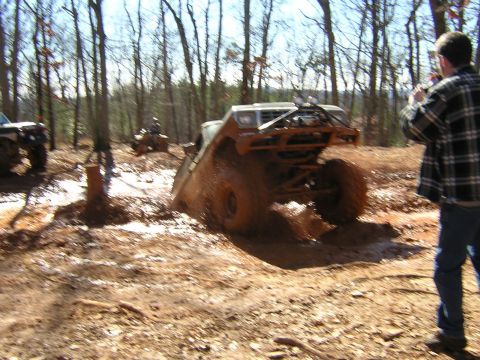 1979 Ford Bronco - An off-road vehicle navigates a muddy trail, with another vehicle and an ATV visible in the background.