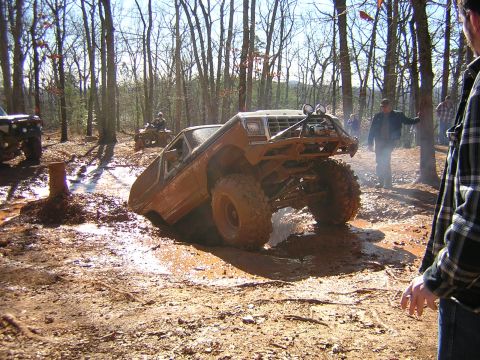 1979 Ford Bronco - An off-road vehicle is stuck in a mud pit during an outdoor event with spectators nearby.