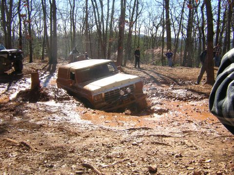 1979 Ford Bronco - A Ford Bronco is stuck deep in the mud during an off-road event, with another vehicle visible in the background.