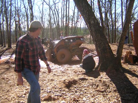 1979 Ford Bronco - An off-road vehicle is stuck in a muddy area, with several people observing the situation.