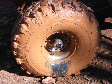 1979 Ford Bronco - A close-up view of a heavily mud-caked tire and wheel, suggesting off-road use.