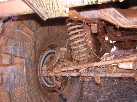 1979 Ford Bronco - Close-up view of a heavily mud-covered vehicle's suspension system and tire.