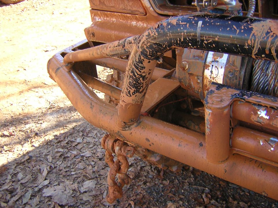 Mud-covered front bumper and winch with a chain hanging down