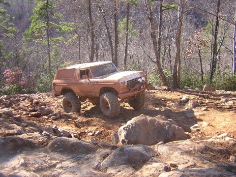 1979 Ford Bronco - This lifted 1978 Ford Bronco is tackling a challenging off-road course in a wooded area.