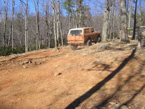 1979 Ford Bronco - A 1979 Ford Bronco navigates a dusty, wooded trail during an outdoor event.