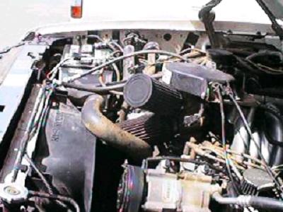 1993 Ford Bronco - The engine bay of a vehicle, an aftermarket air filter and various hoses and components.