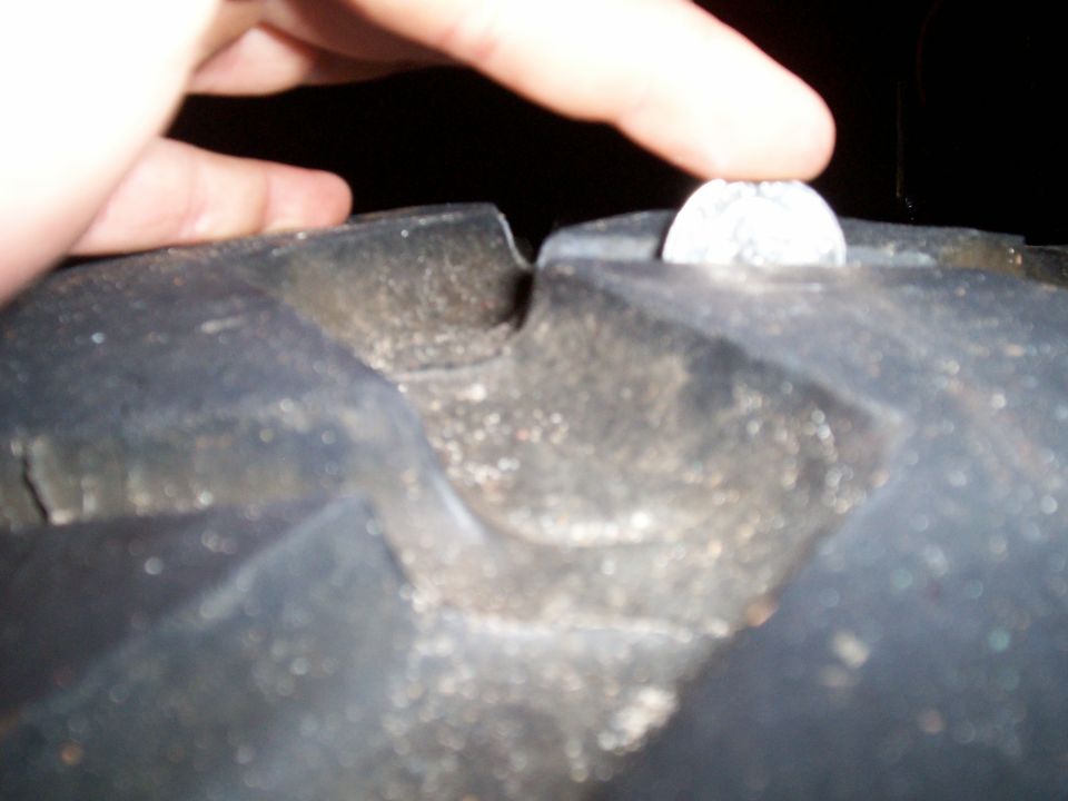 Finger and coin placed in tire tread to show depth