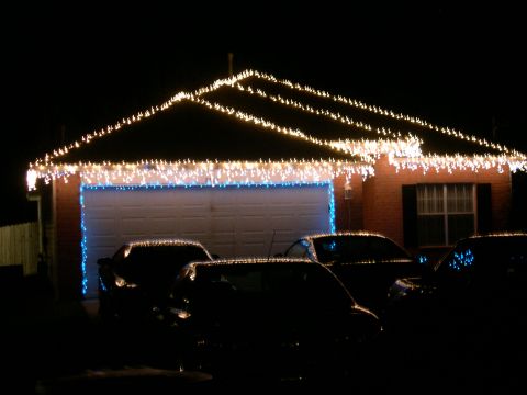 1997 Ford Probe - A house is adorned with festive lights, with several vehicles parked in the driveway under the night sky.